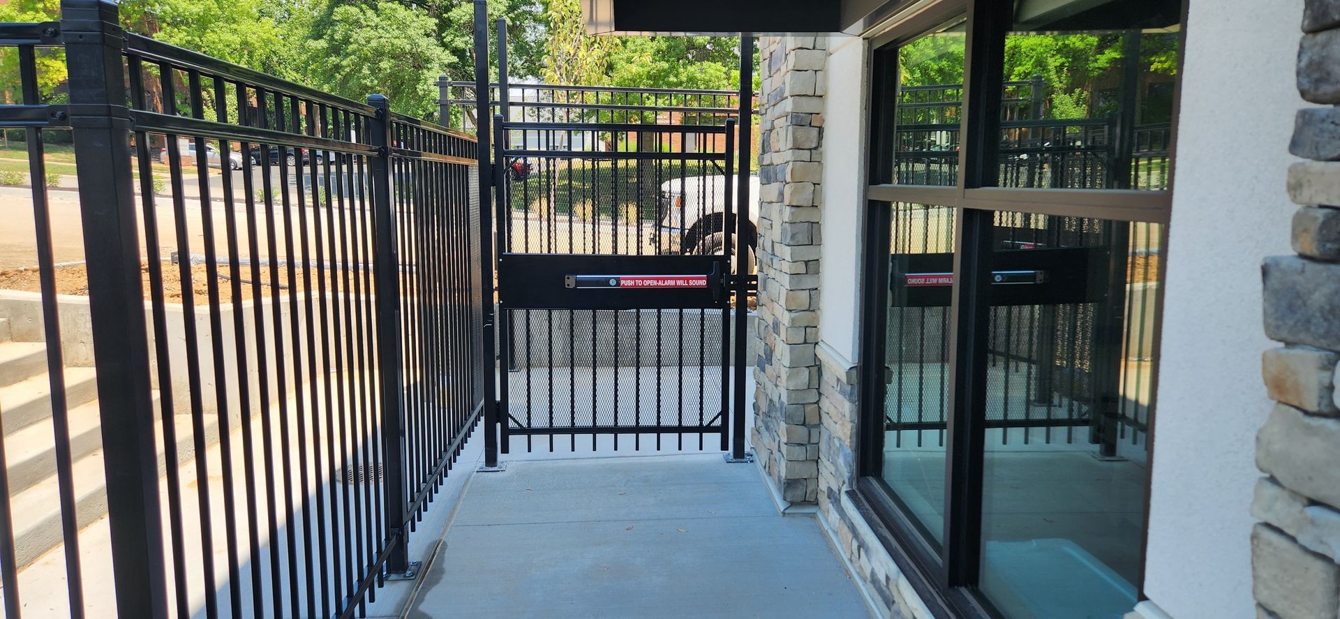 A wrought iron fence surrounds a walkway leading to a building.