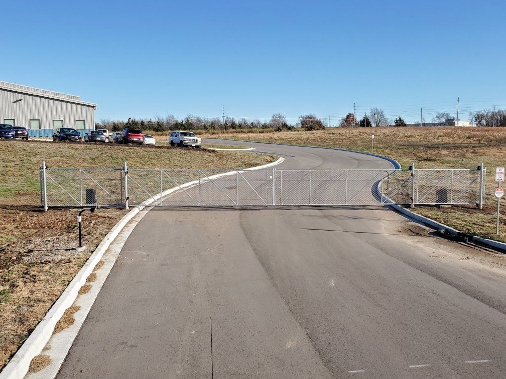 A road with a fence and a building in the background