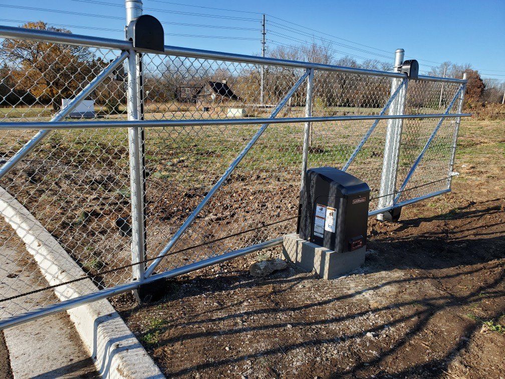 A sliding gate with a motor attached to it is sitting next to a chain link fence.