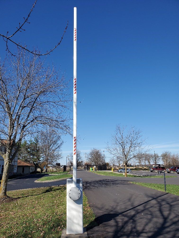 A tall white pole is sitting on the side of a road.