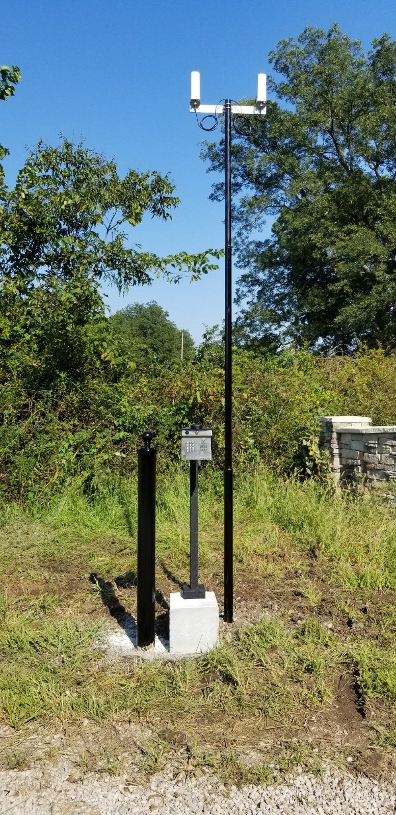 A weather station is sitting in the middle of a grassy field.