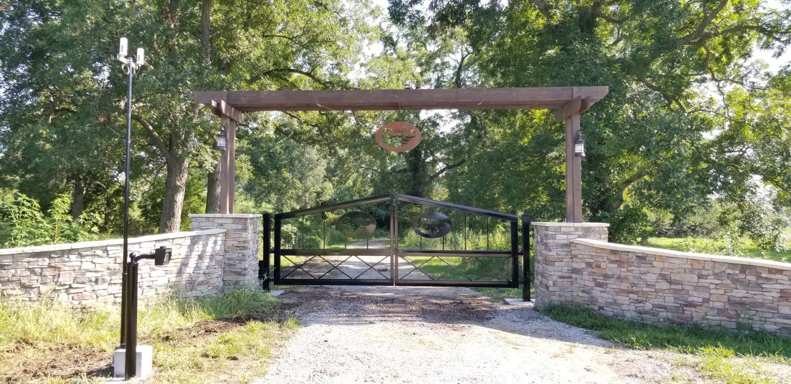 There is a gate in the middle of a dirt road surrounded by trees.