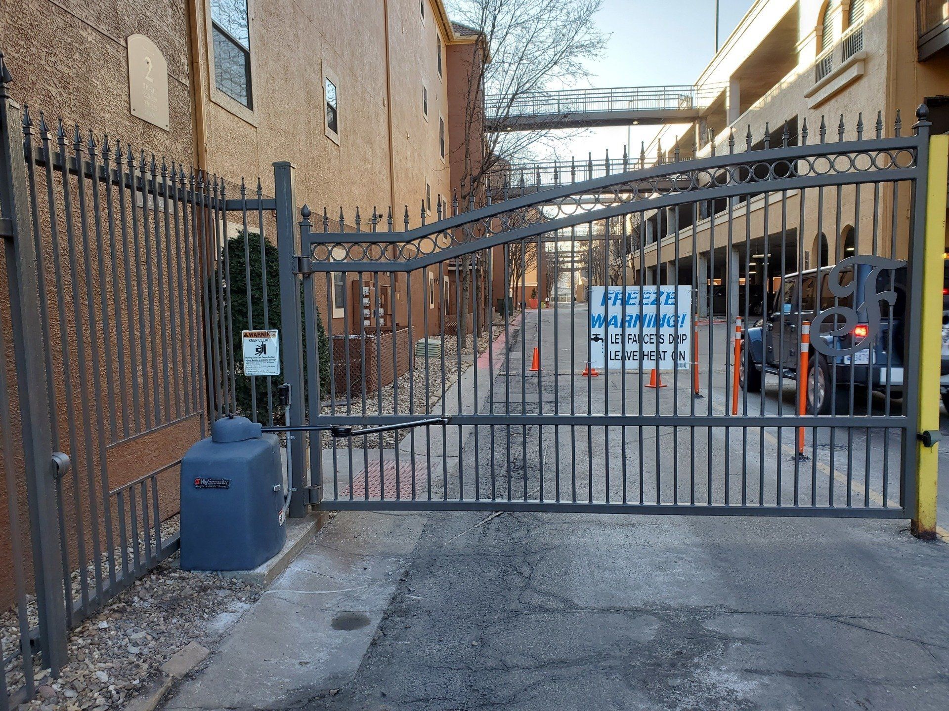 A metal gate is open to a parking lot.