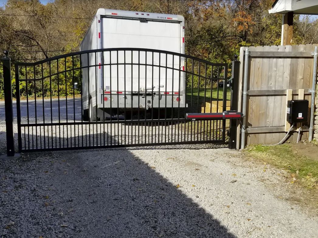A white truck is parked behind a metal gate.