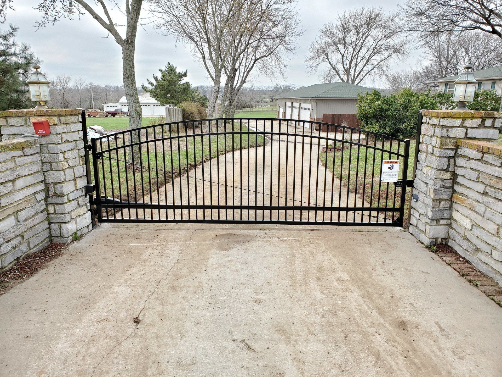A black metal gate is open to a dirt road.