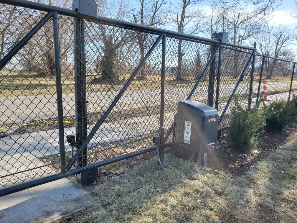 A black chain link fence with a black box in the middle of it.