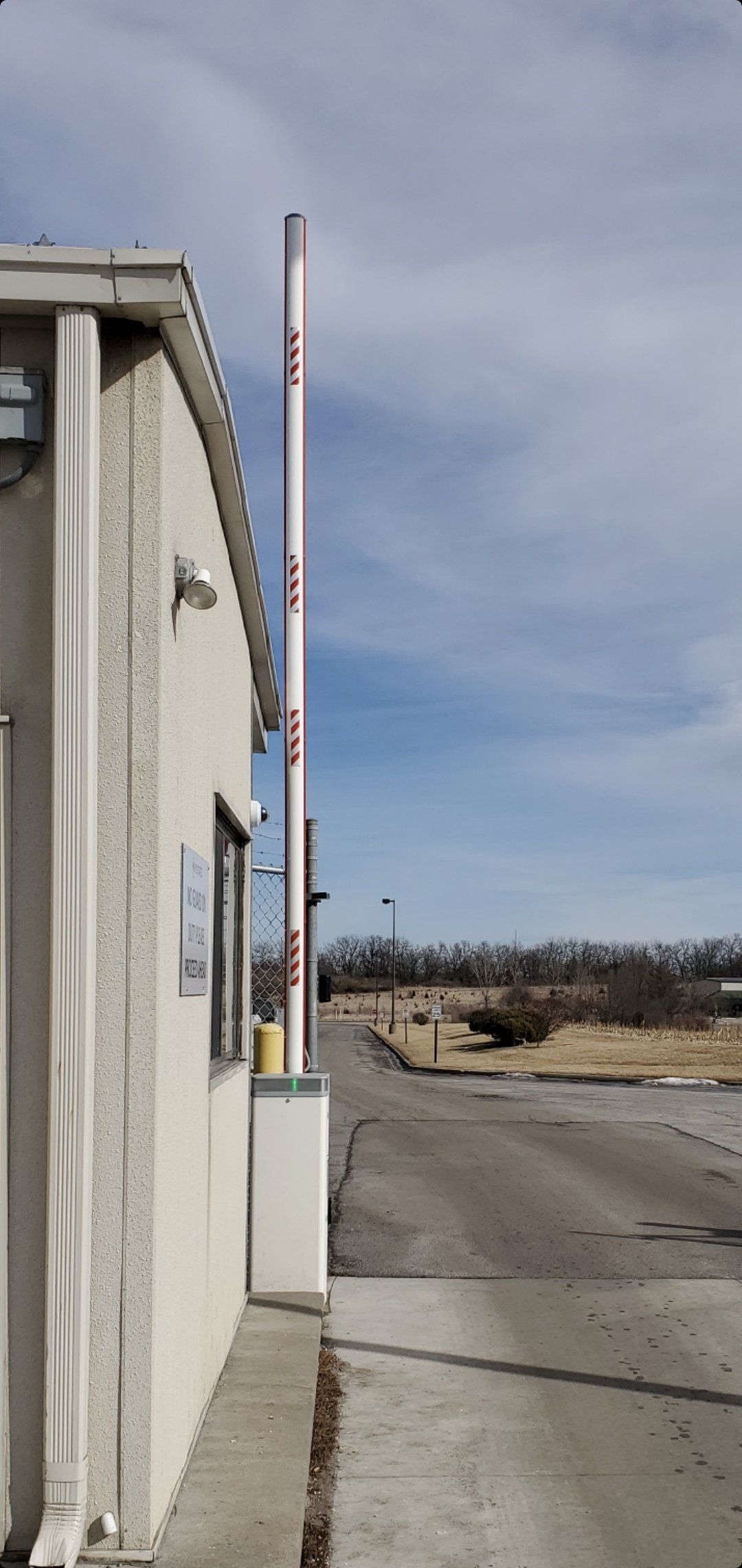 A white building with a red and white pole in front of it.