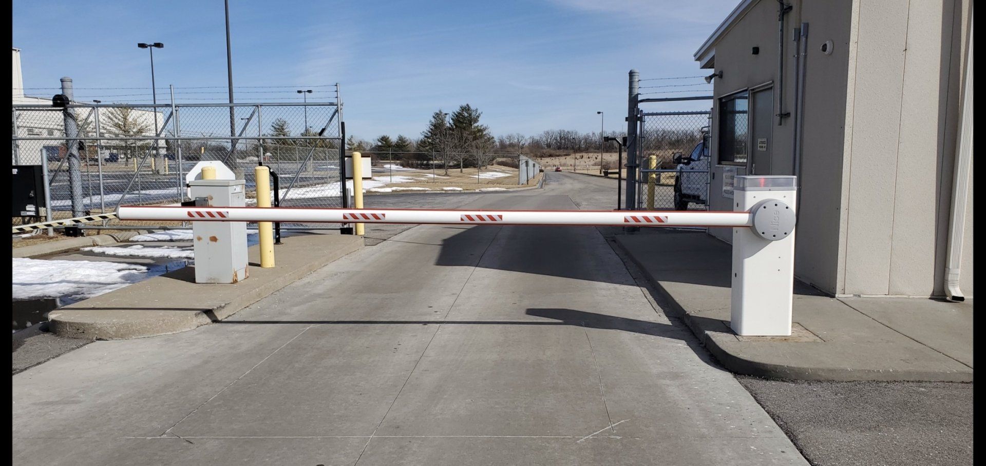 A white barrier is blocking the entrance to a parking lot.