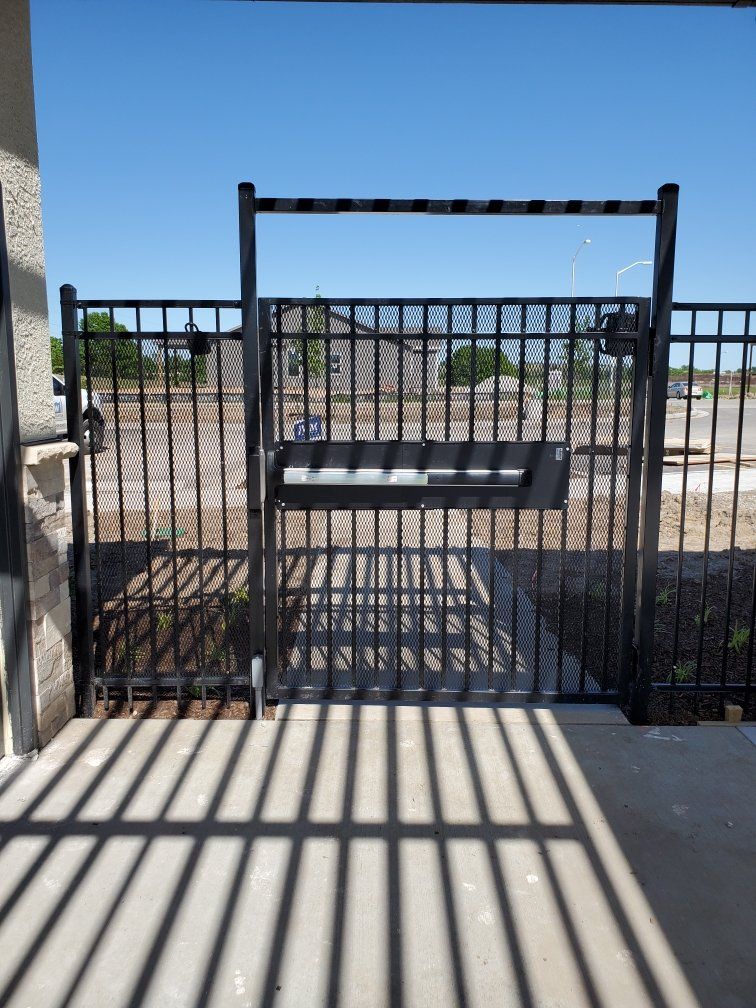 A fence with a gate and shadows on the ground
