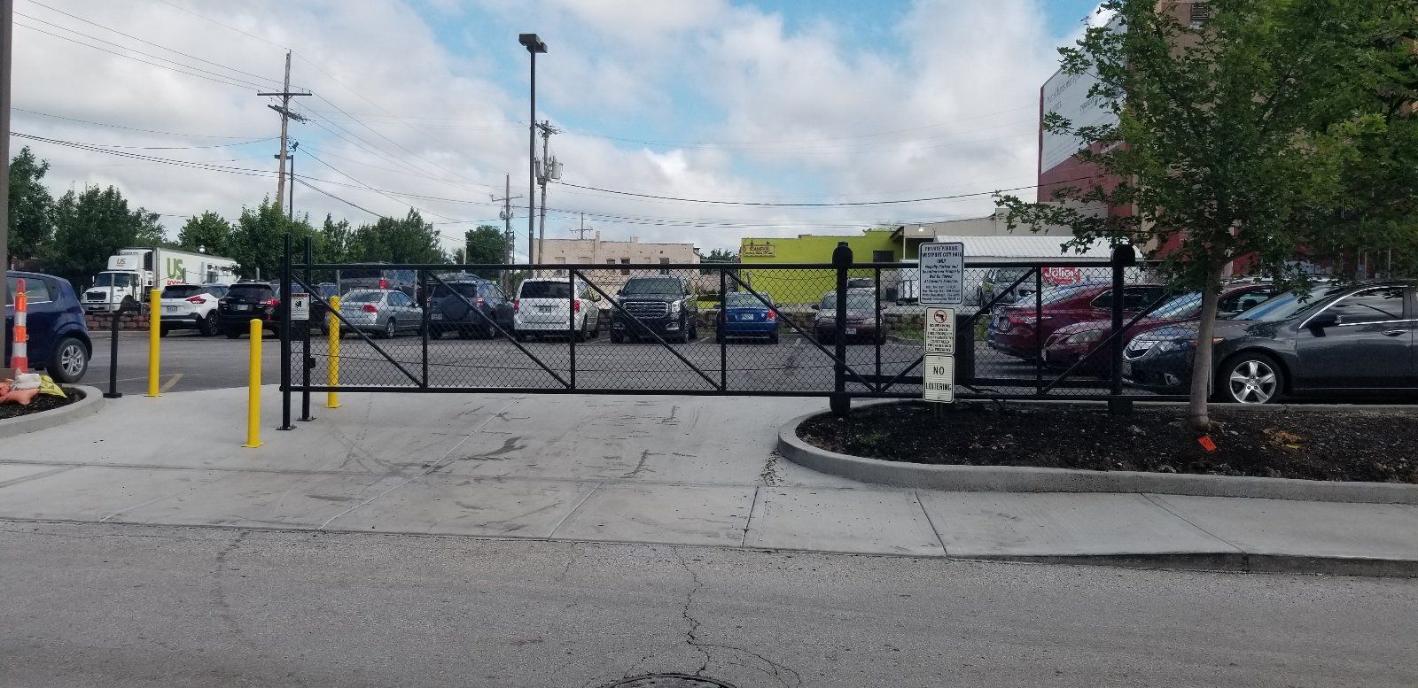 A lot of cars are parked in a parking lot behind a gate.