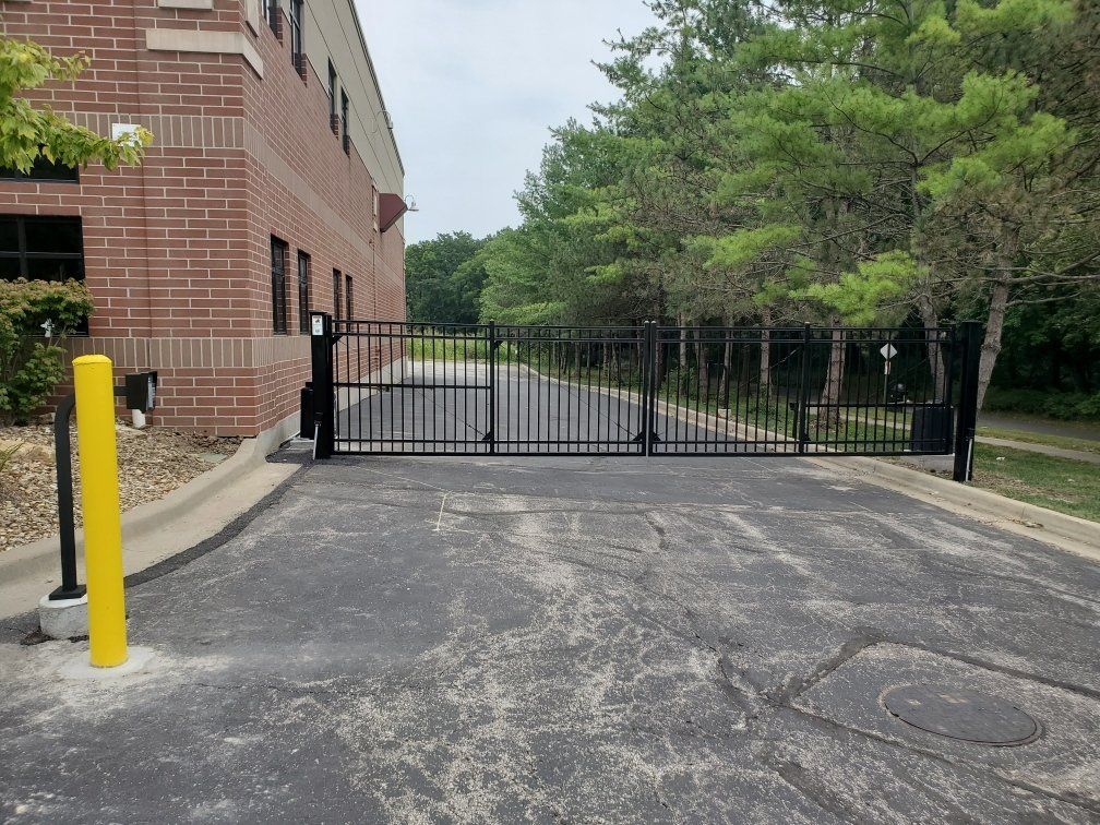 A brick building with a black gate and a yellow pole in front of it
