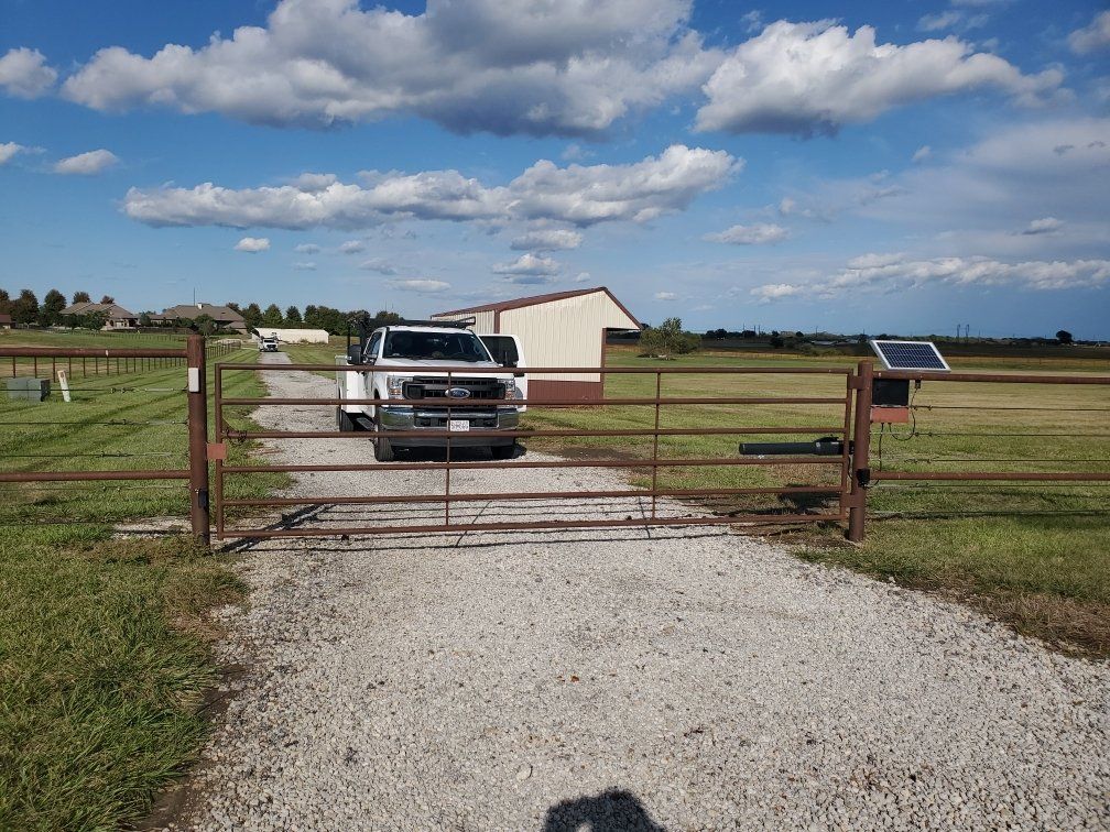 A truck is driving through a gate on a gravel road.