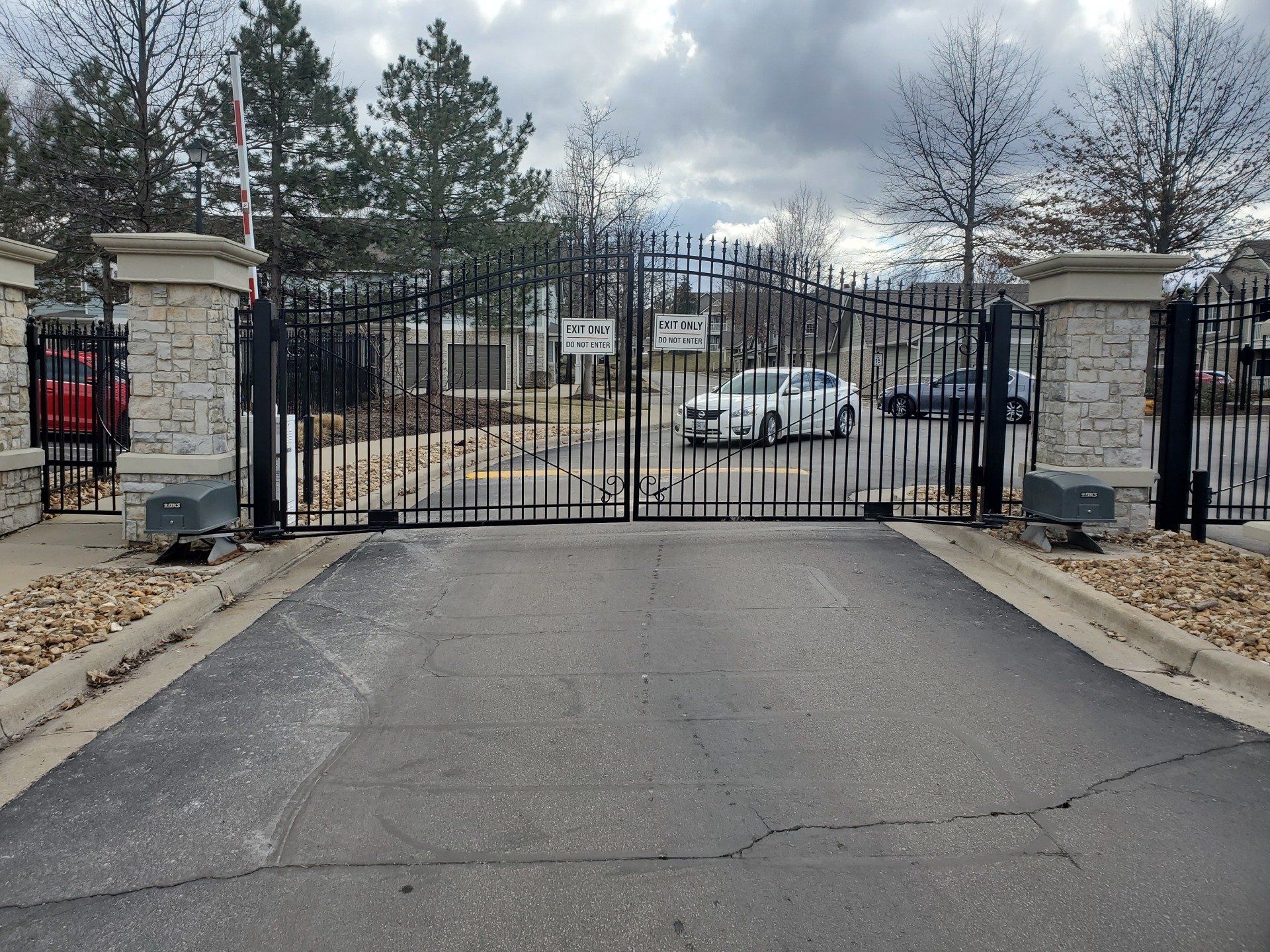 A car is parked in front of a gate that says no parking
