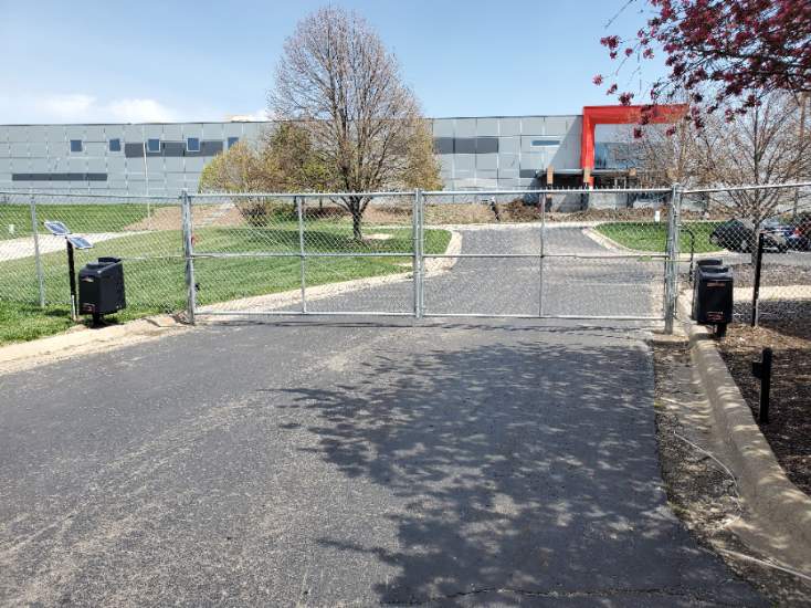 A gate is closed in front of a large building.