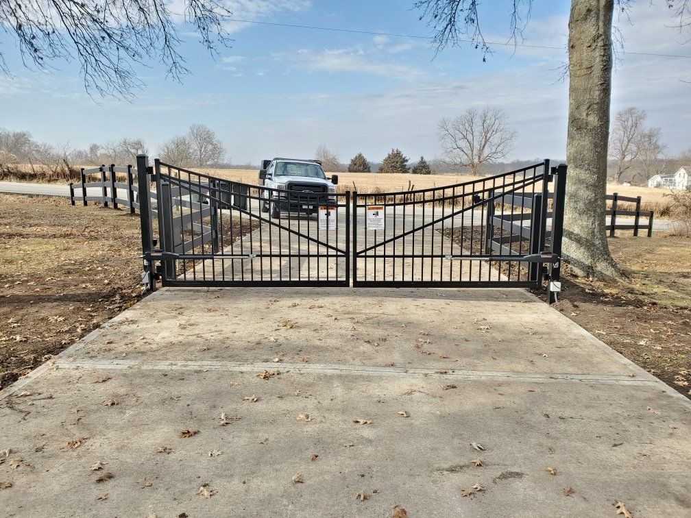 A black metal gate is sitting on top of a concrete driveway.