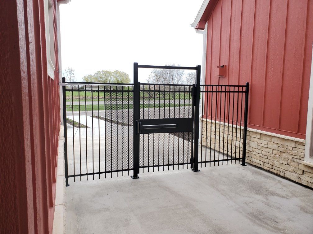 A black fence is in front of a red building
