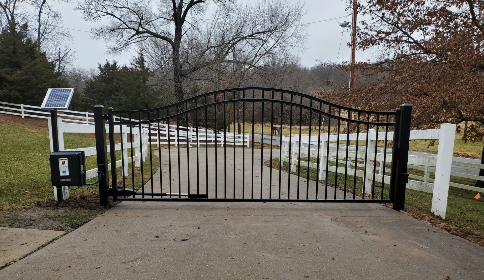 A black metal gate with a solar panel on top of it.