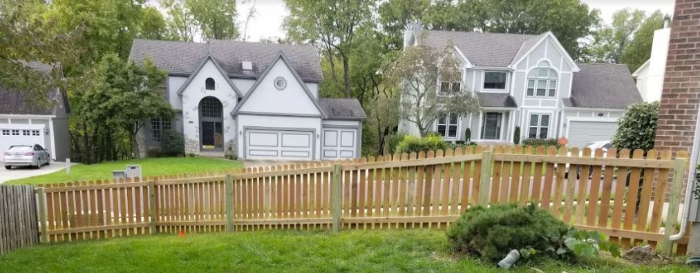 A large white house with a wooden fence in front of it.