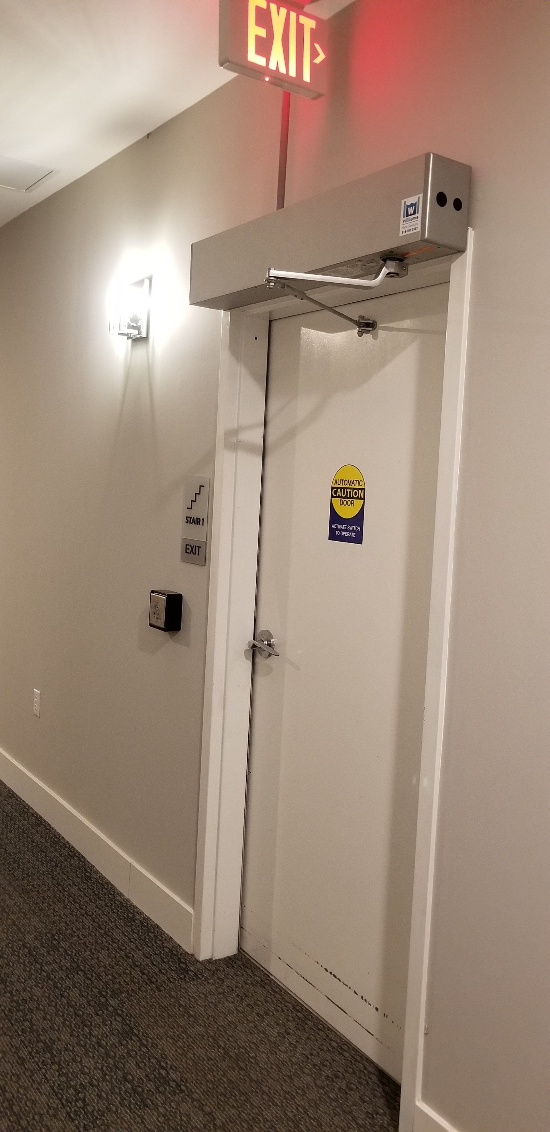 A white door with a red exit sign above it in a hallway.