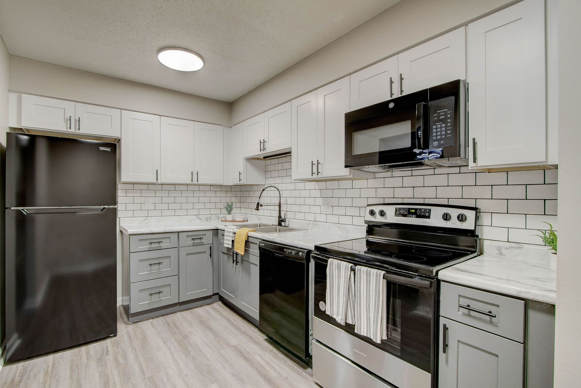 Modern kitchen with white and gray cabinets, stainless steel appliances, and white subway tile backsplash.