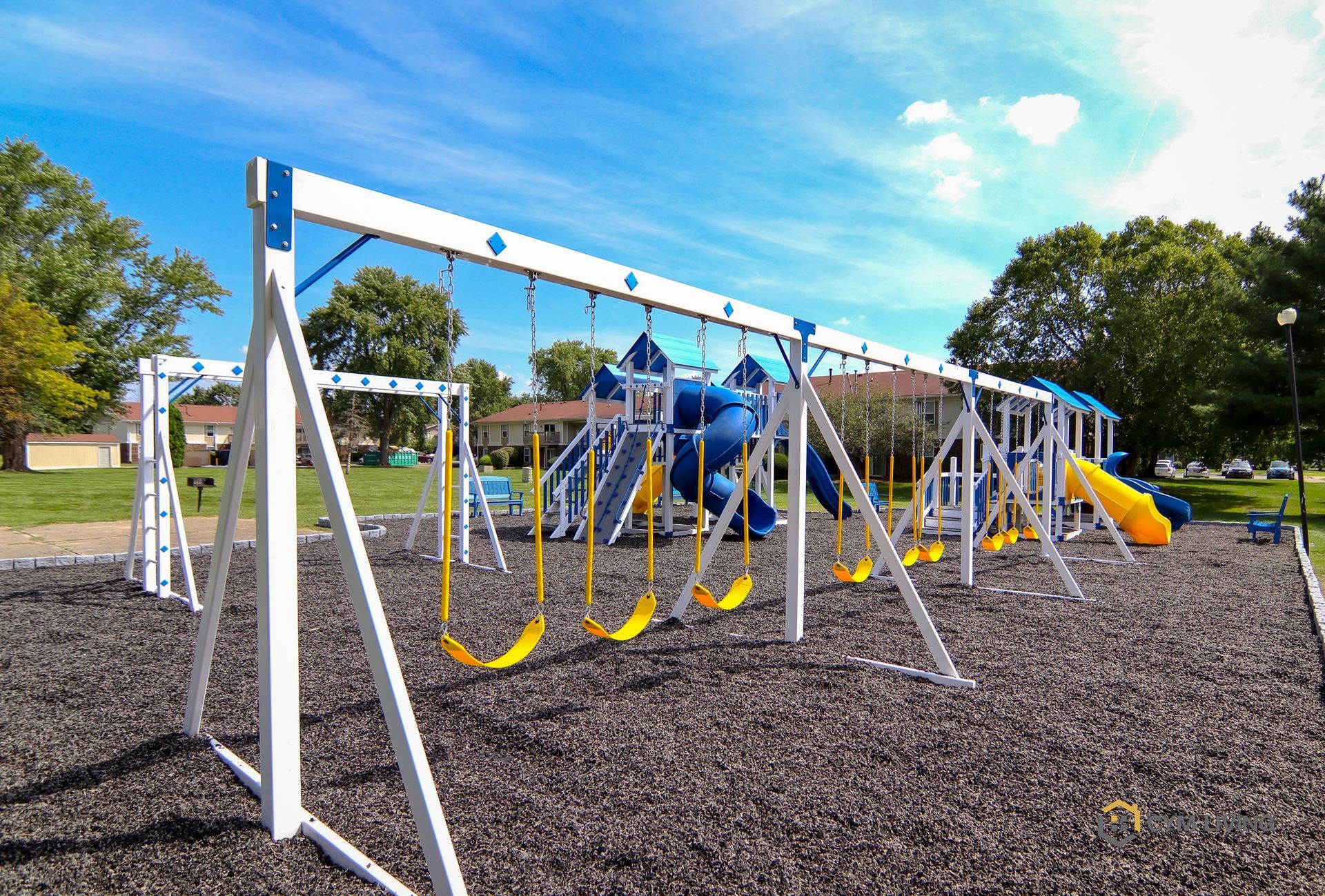 Playground with blue and white structures and yellow swings under a blue sky.