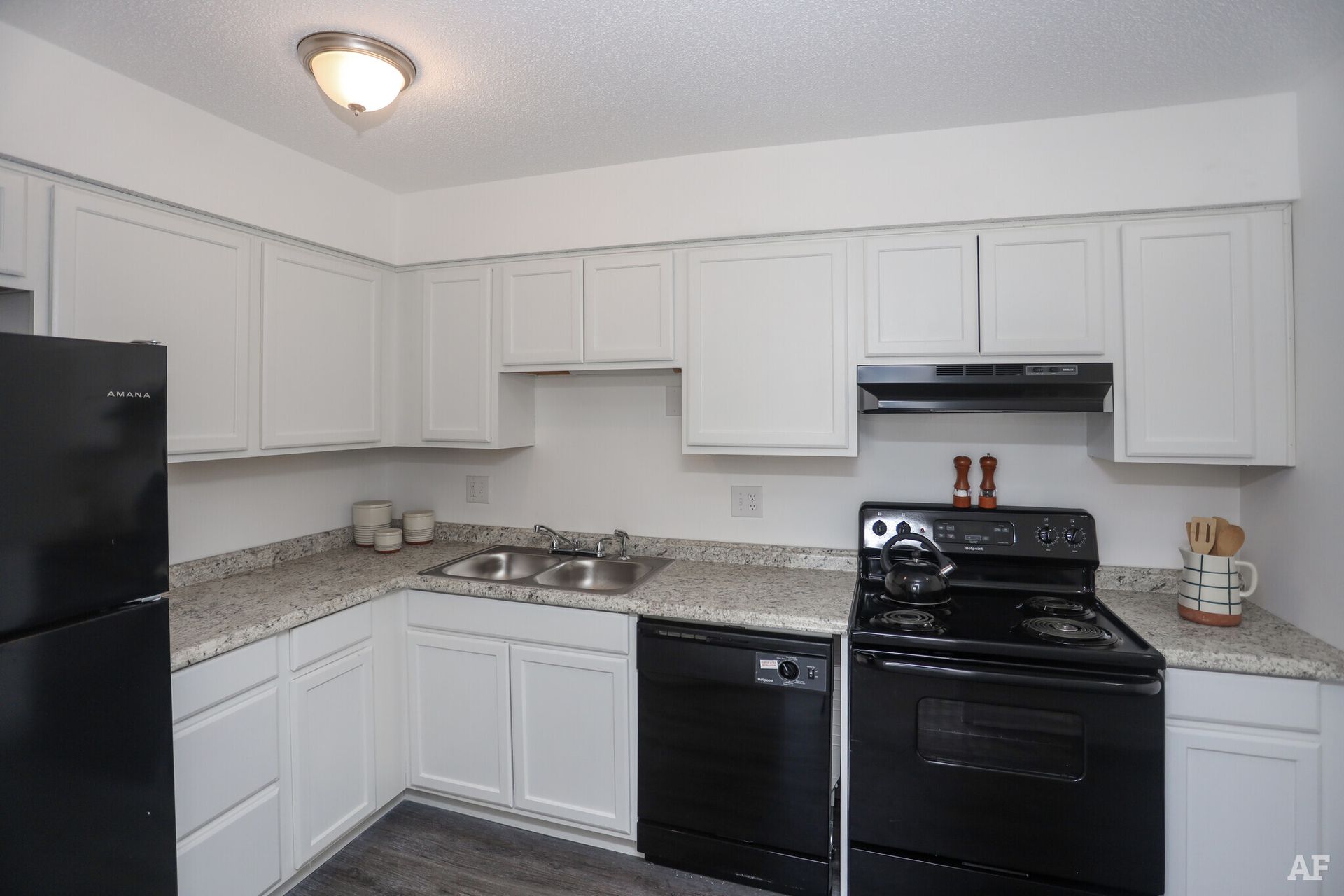 White kitchen with black appliances: refrigerator, stove, and dishwasher.