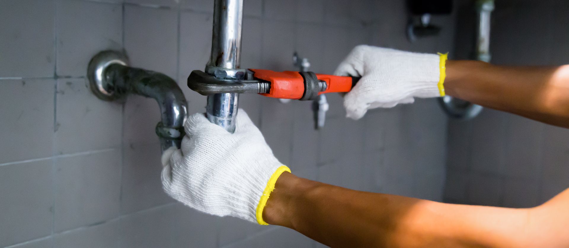 Plumber Using a Wrench to Fix Drain Pipes — America NW Plumbing, Heating, and Cooling in Post Falls, ID