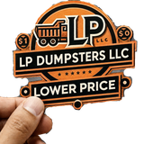 Hand holding an orange and black LP Dumpsters LLC sticker logo with “Lower Price” text