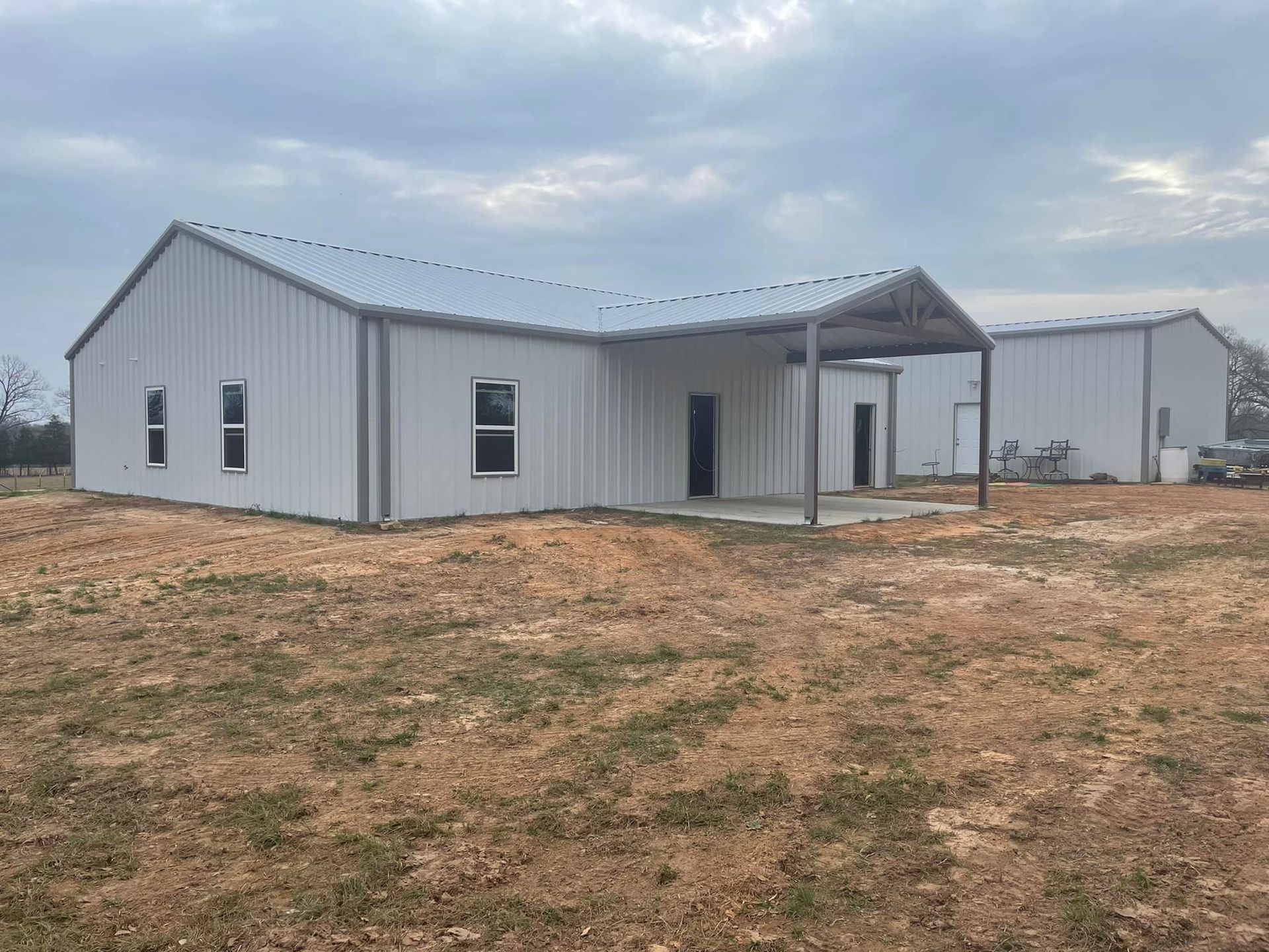 A large white building is sitting in the middle of a field.