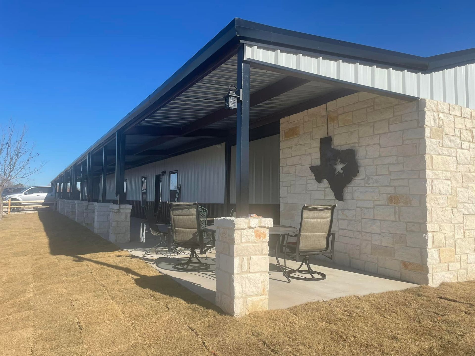 A patio with chairs and a table in front of a building with a texas sign on the wall.