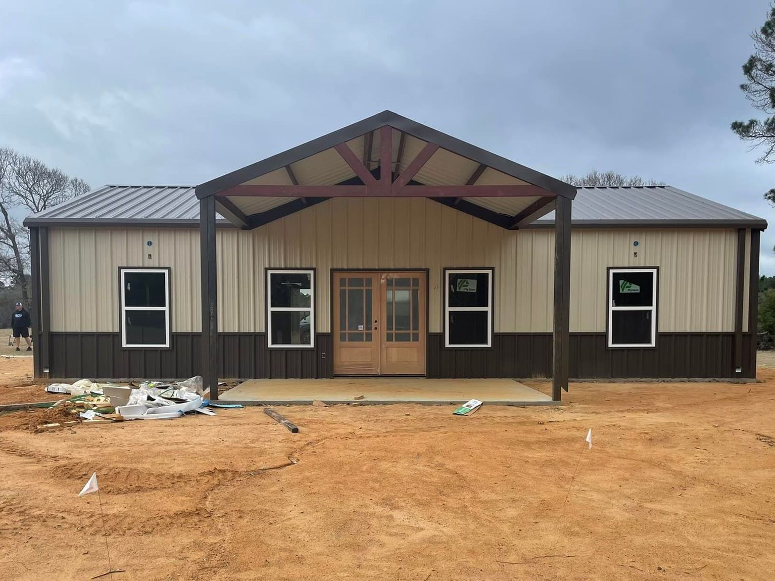 A large house is being built in the middle of a dirt field.