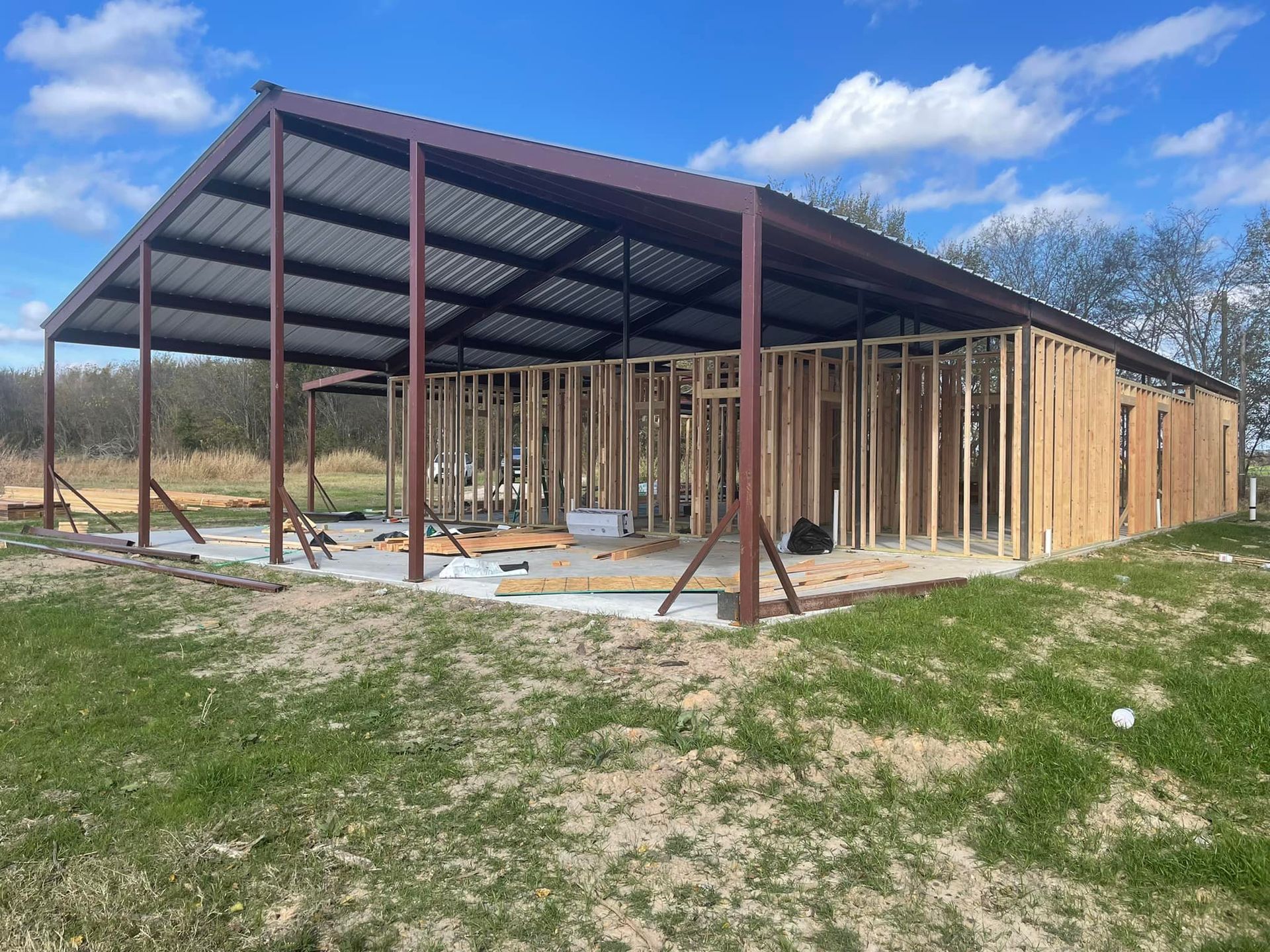 A large building is being built in the middle of a grassy field.