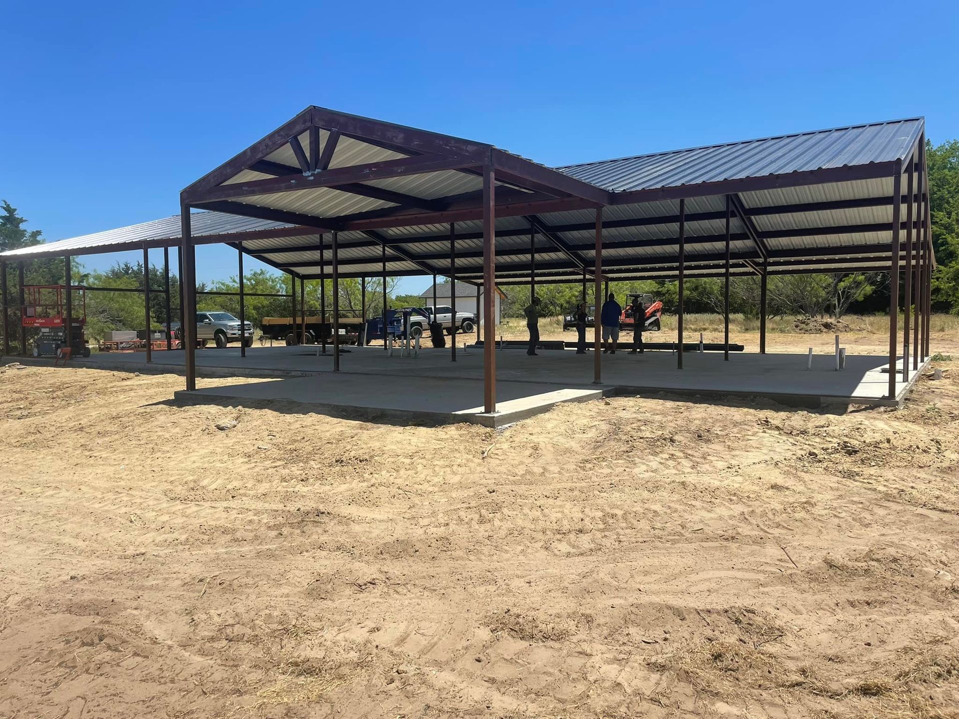 A large metal structure is being built in a dirt field.