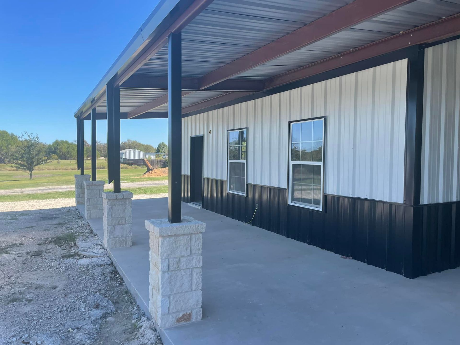 A large metal building with a porch and windows.