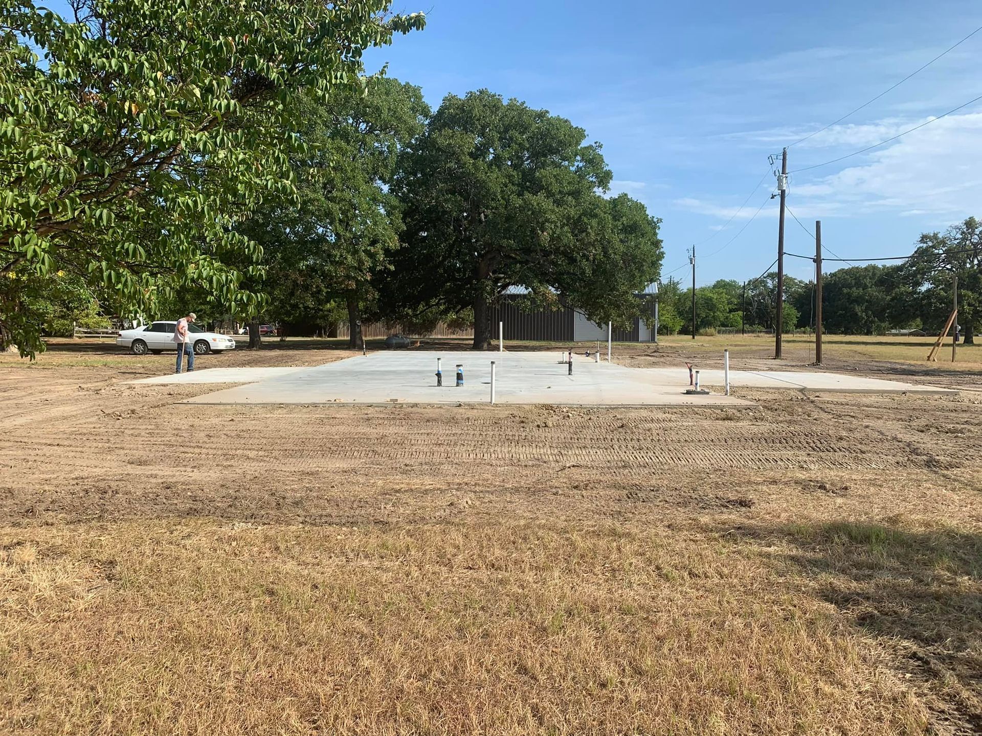 A concrete foundation is being built in a field with trees in the background.