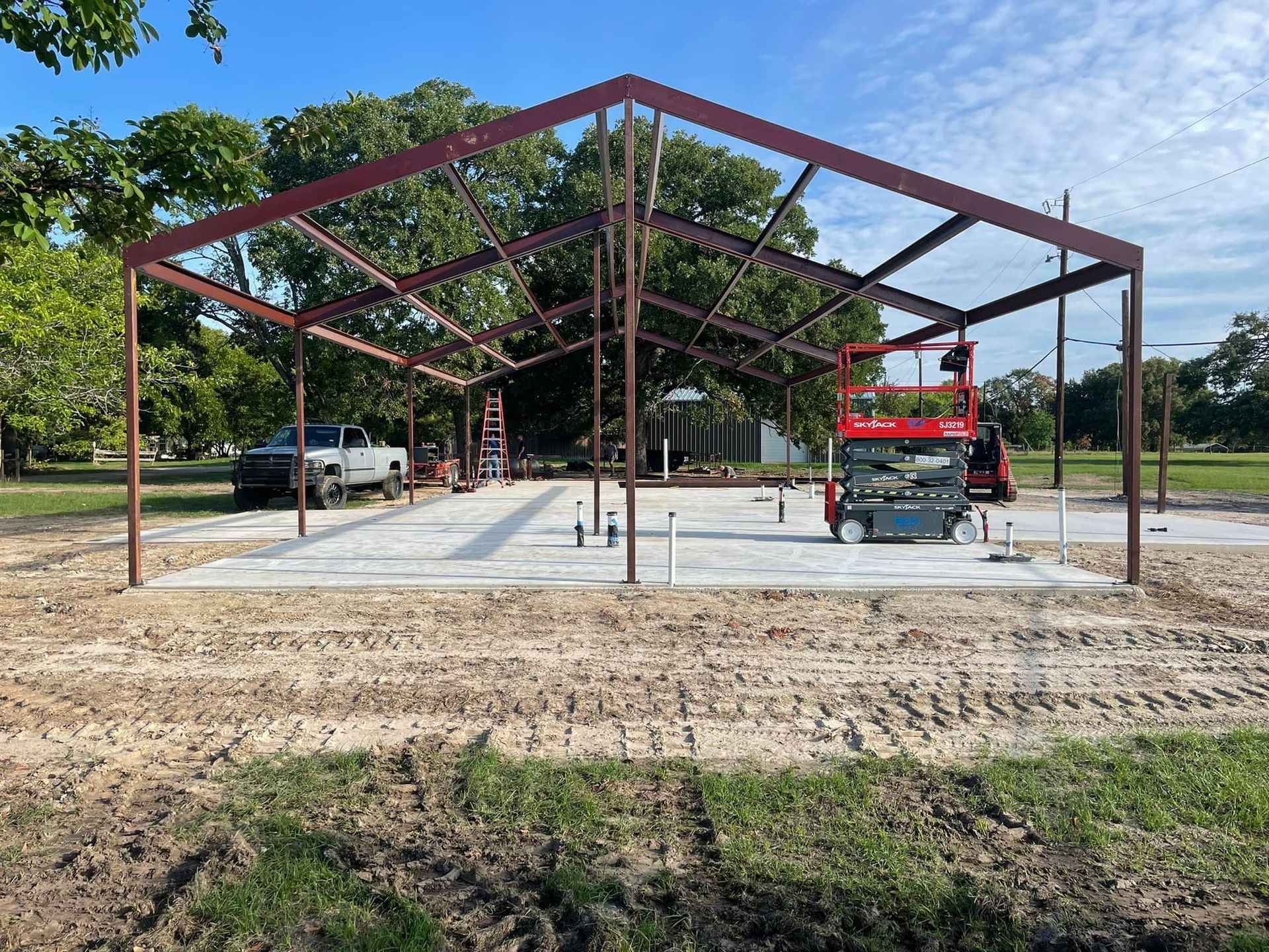 A large metal structure is being built in a dirt field.