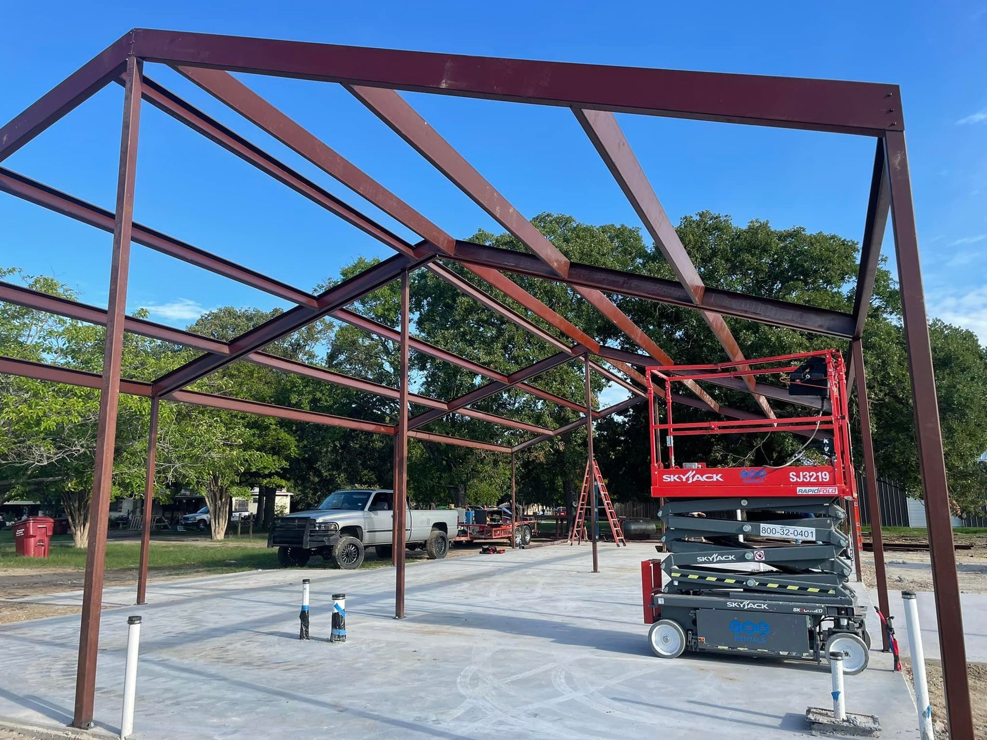 A red scissor lift is sitting in front of a building under construction.