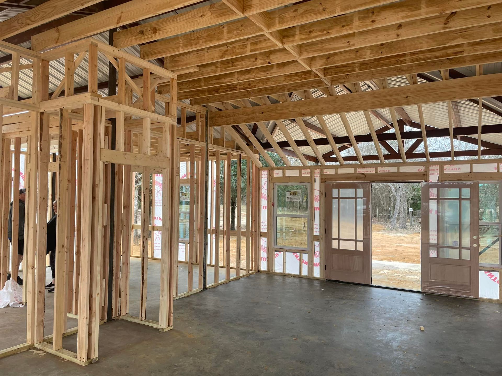 The inside of a house under construction with wooden beams and doors.
