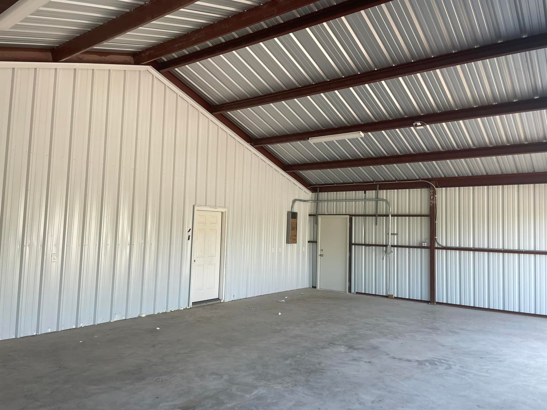 An empty building with a metal roof and white walls