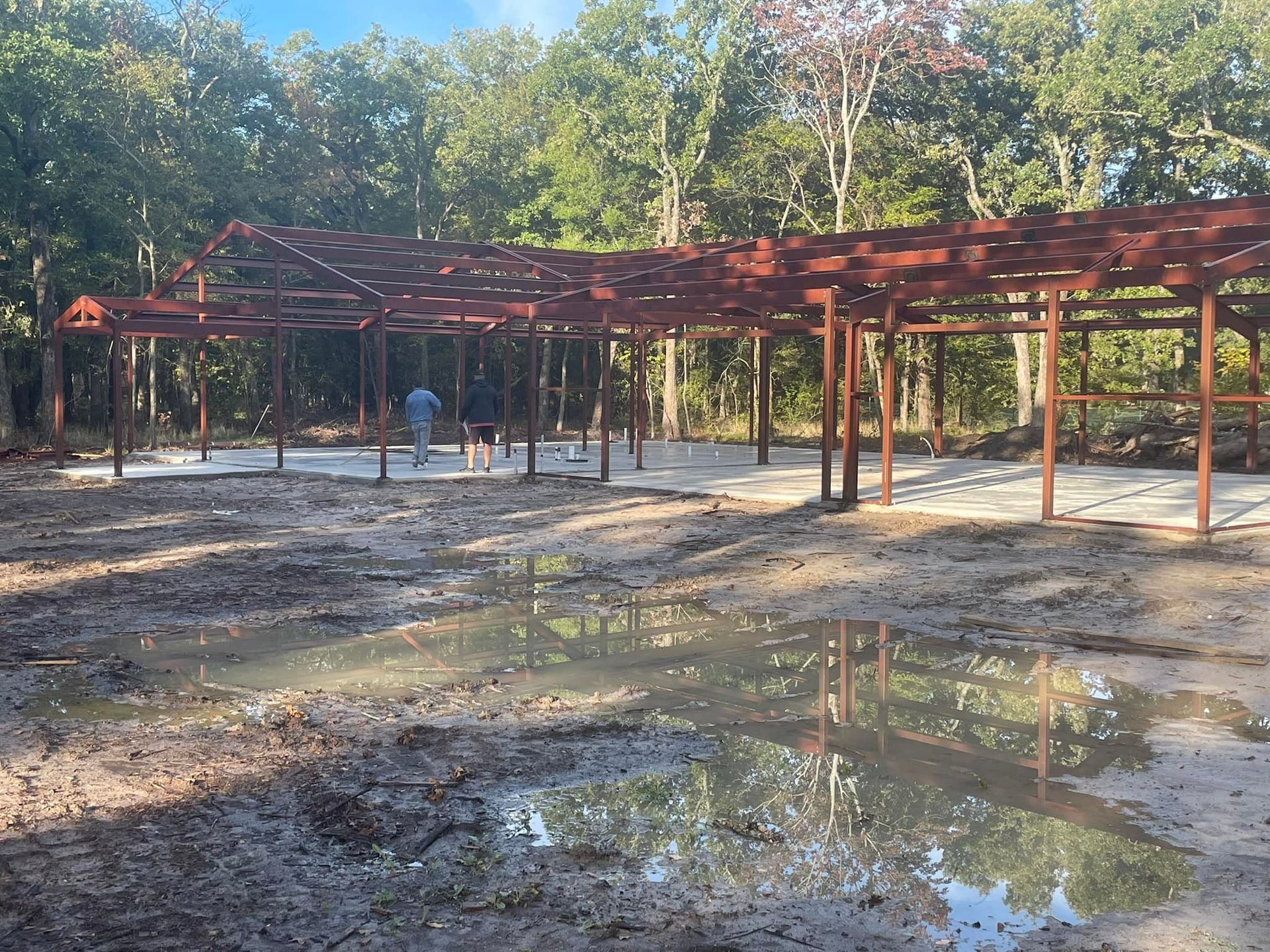 A large metal structure is being built in the middle of a muddy field.