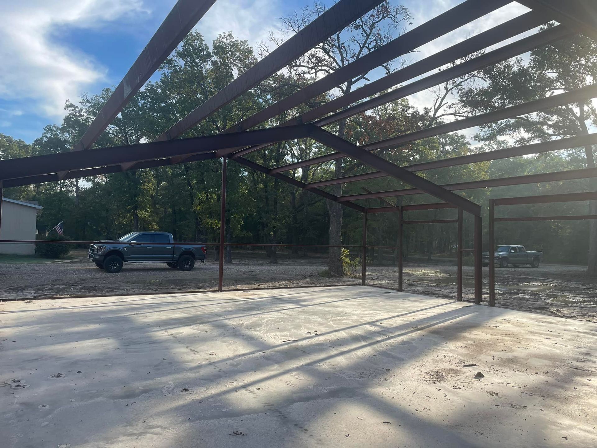 A truck is parked under a metal structure in a parking lot.