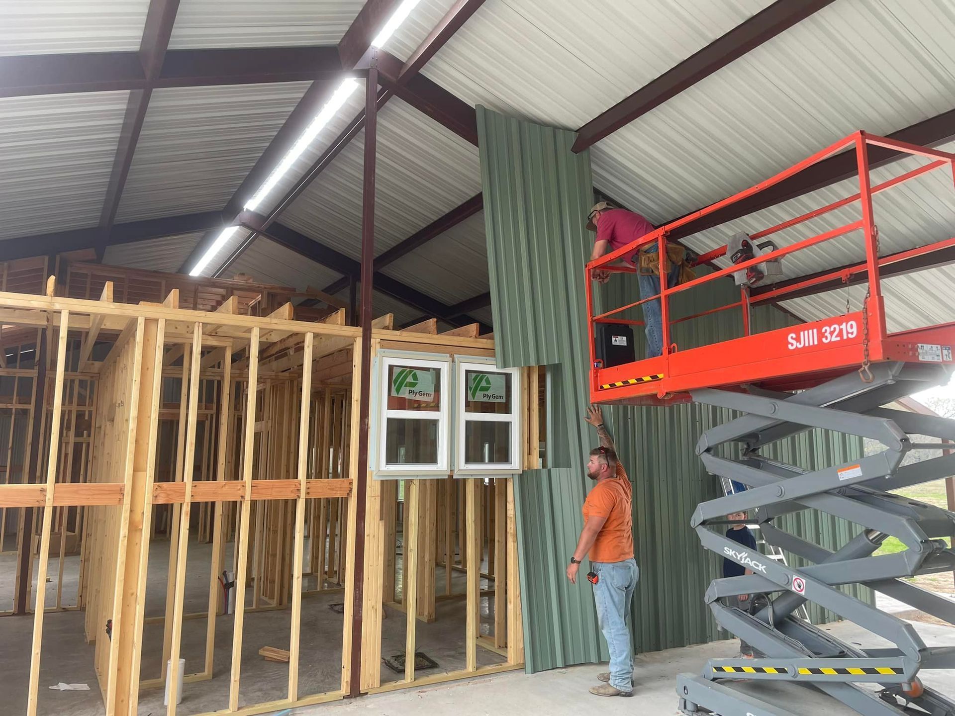 A man is standing on a scissor lift in a building under construction.