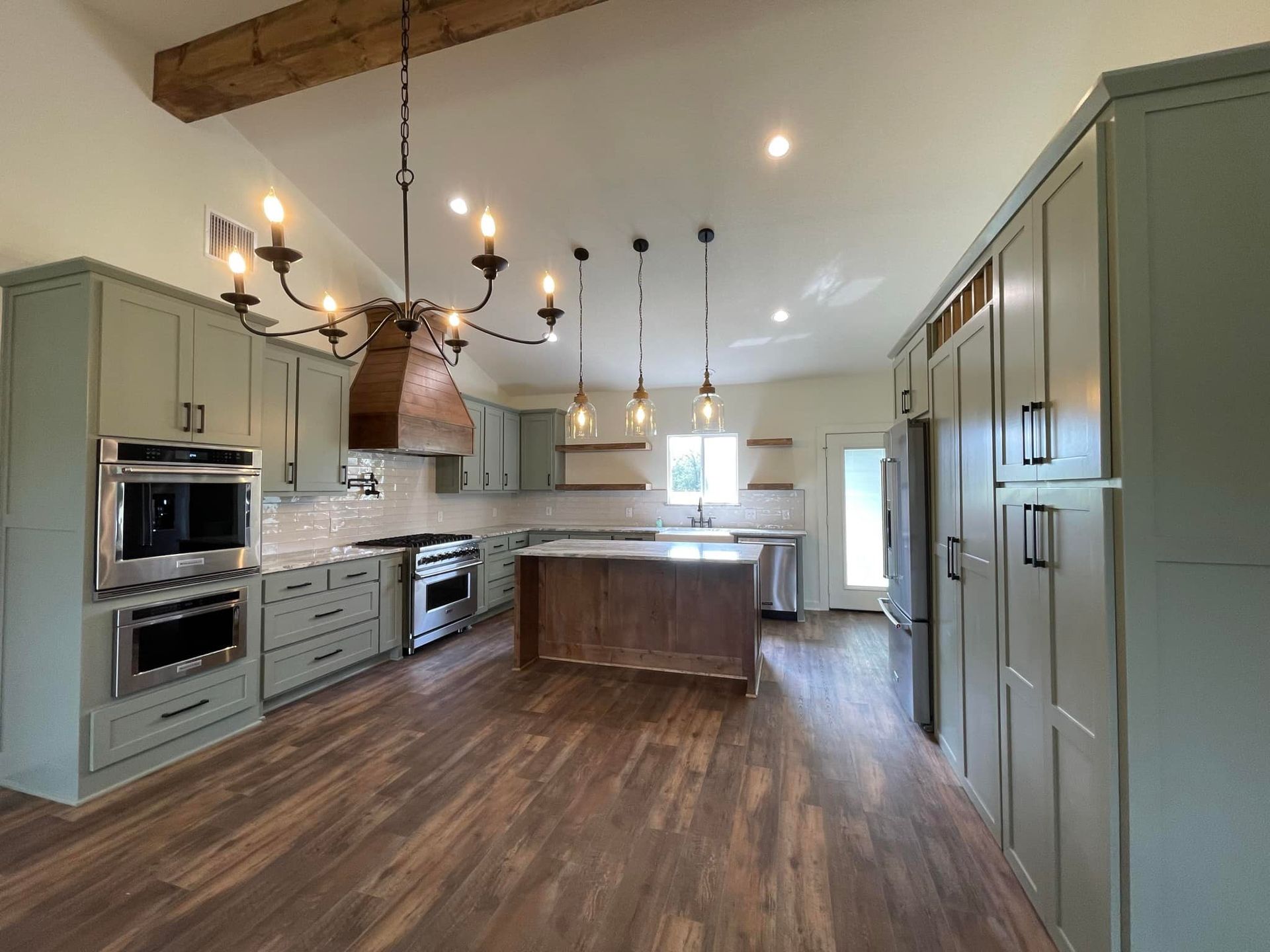 A large kitchen with stainless steel appliances and wooden floors.
