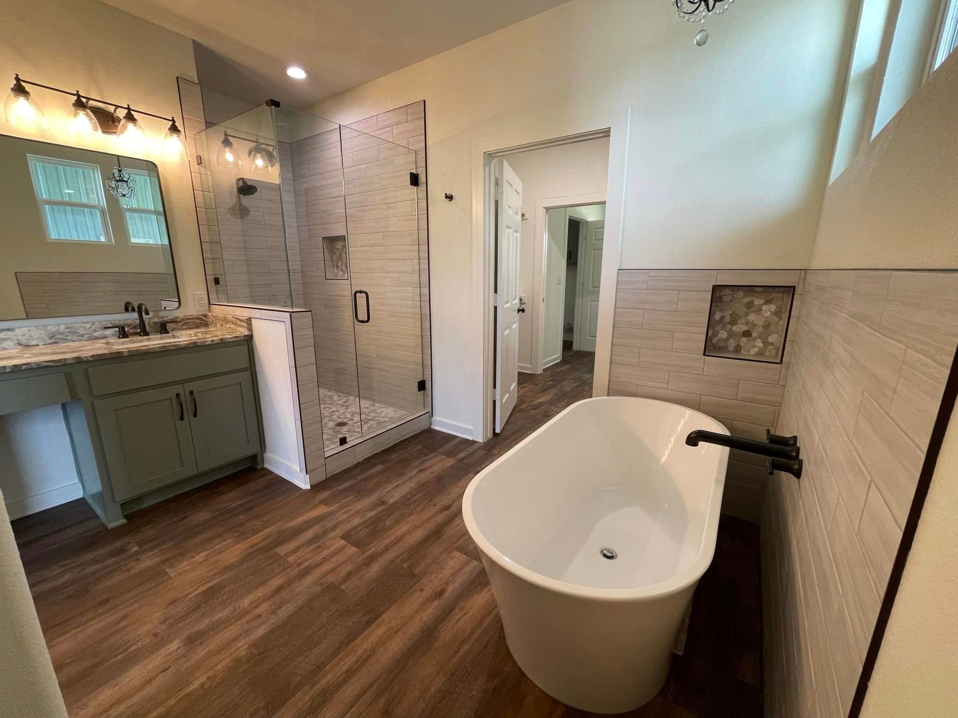 A bathroom with a tub , sink , shower and mirror.