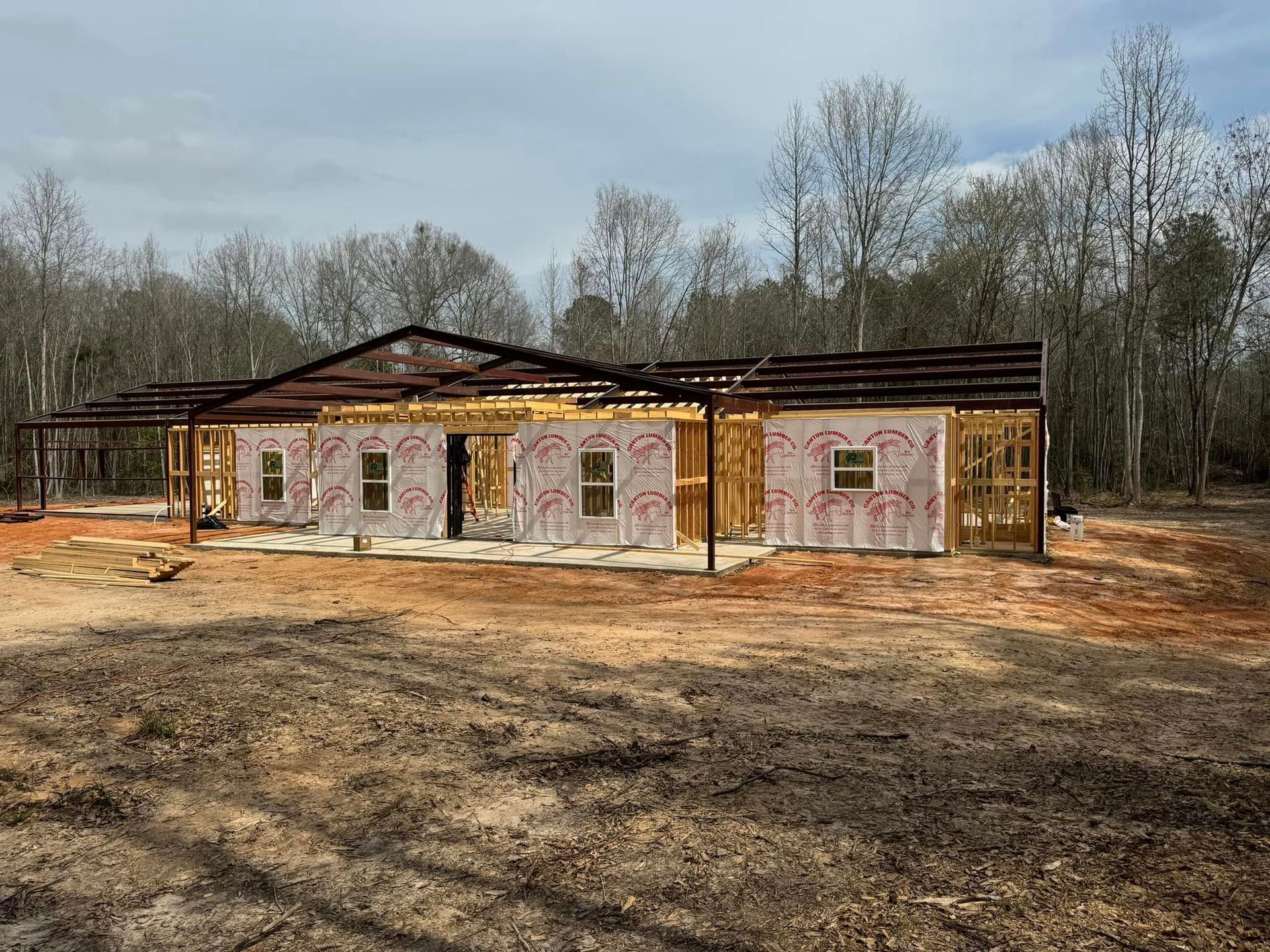A house is being built in a field with trees in the background.