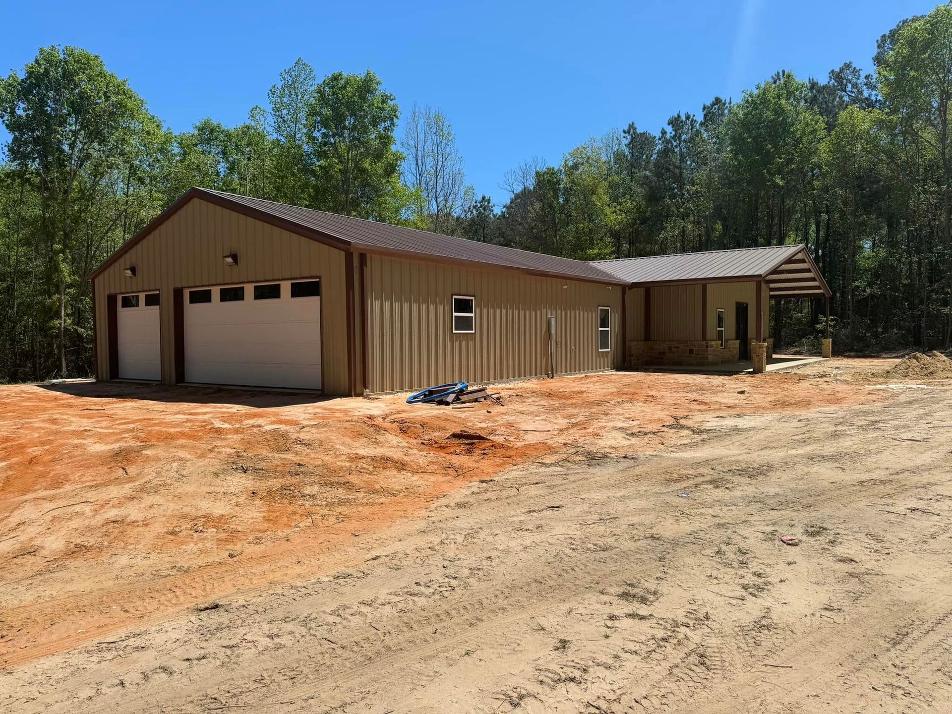 A large building with two garage doors is in the middle of a dirt field