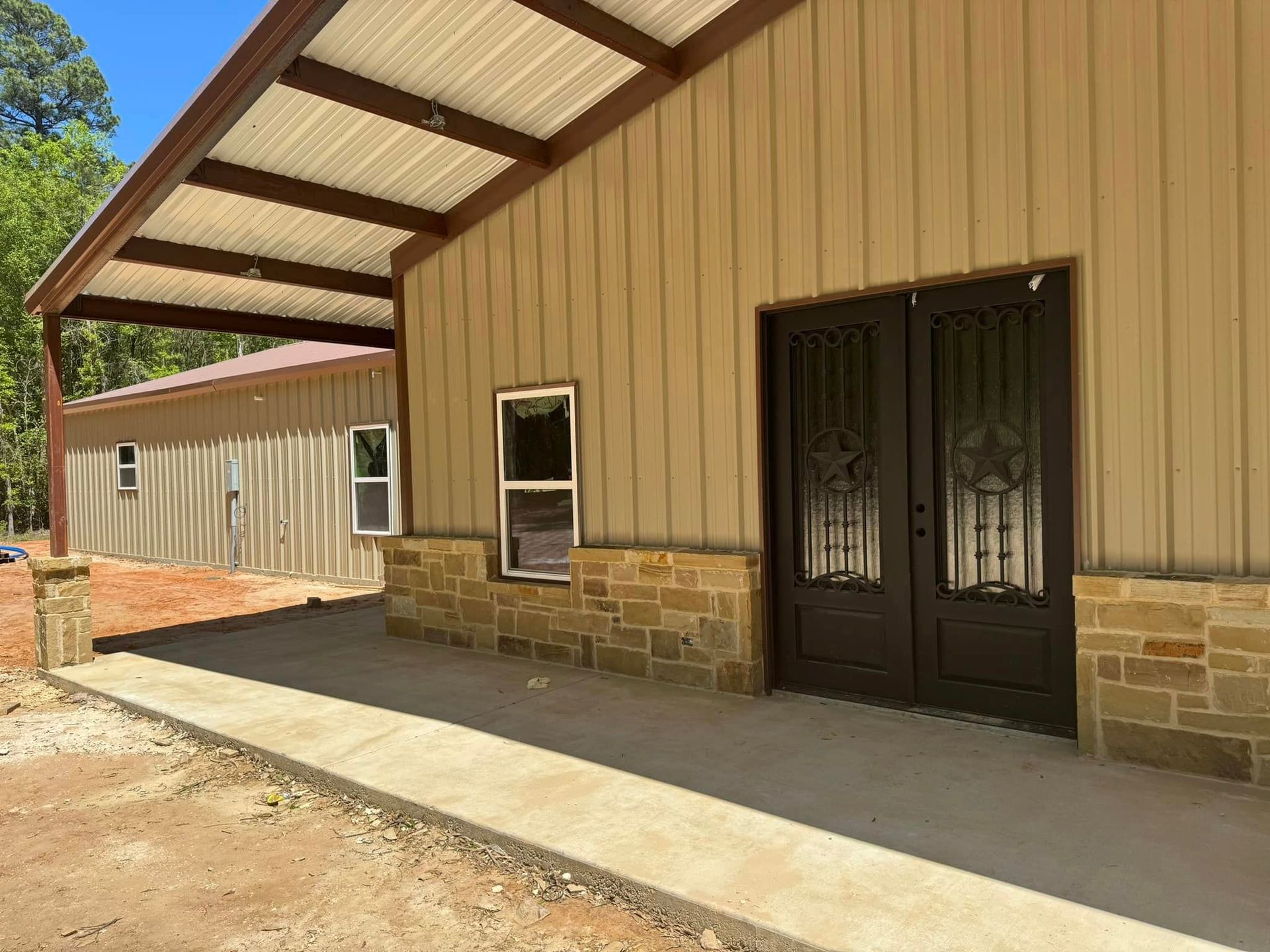 A metal building with a walkway leading to it and a covered porch.