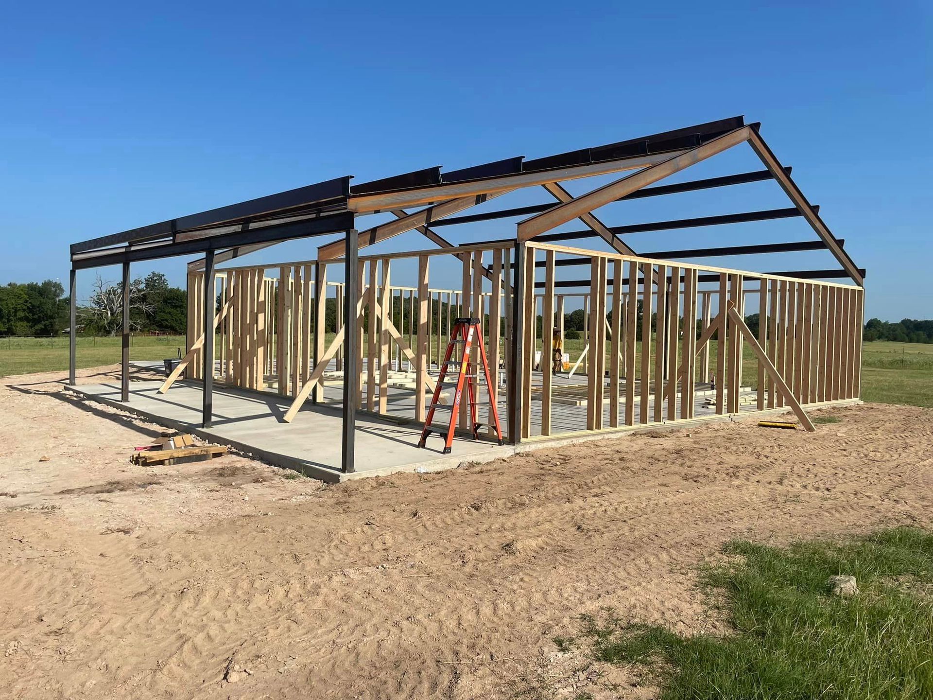 A large wooden structure is being built in a dirt field.