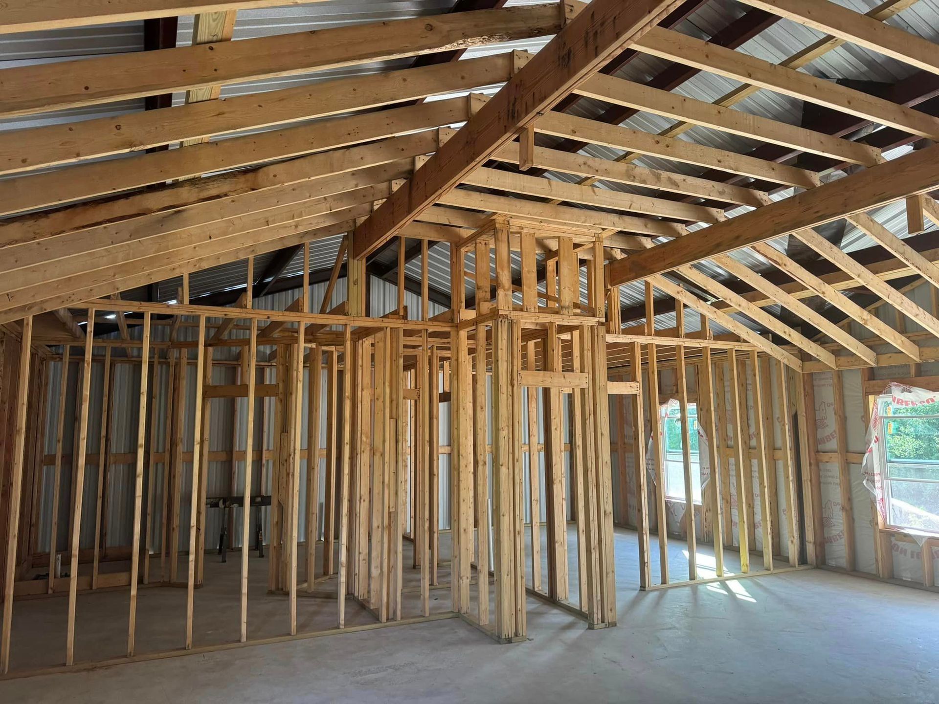 A house is being built with wooden beams and a metal roof.