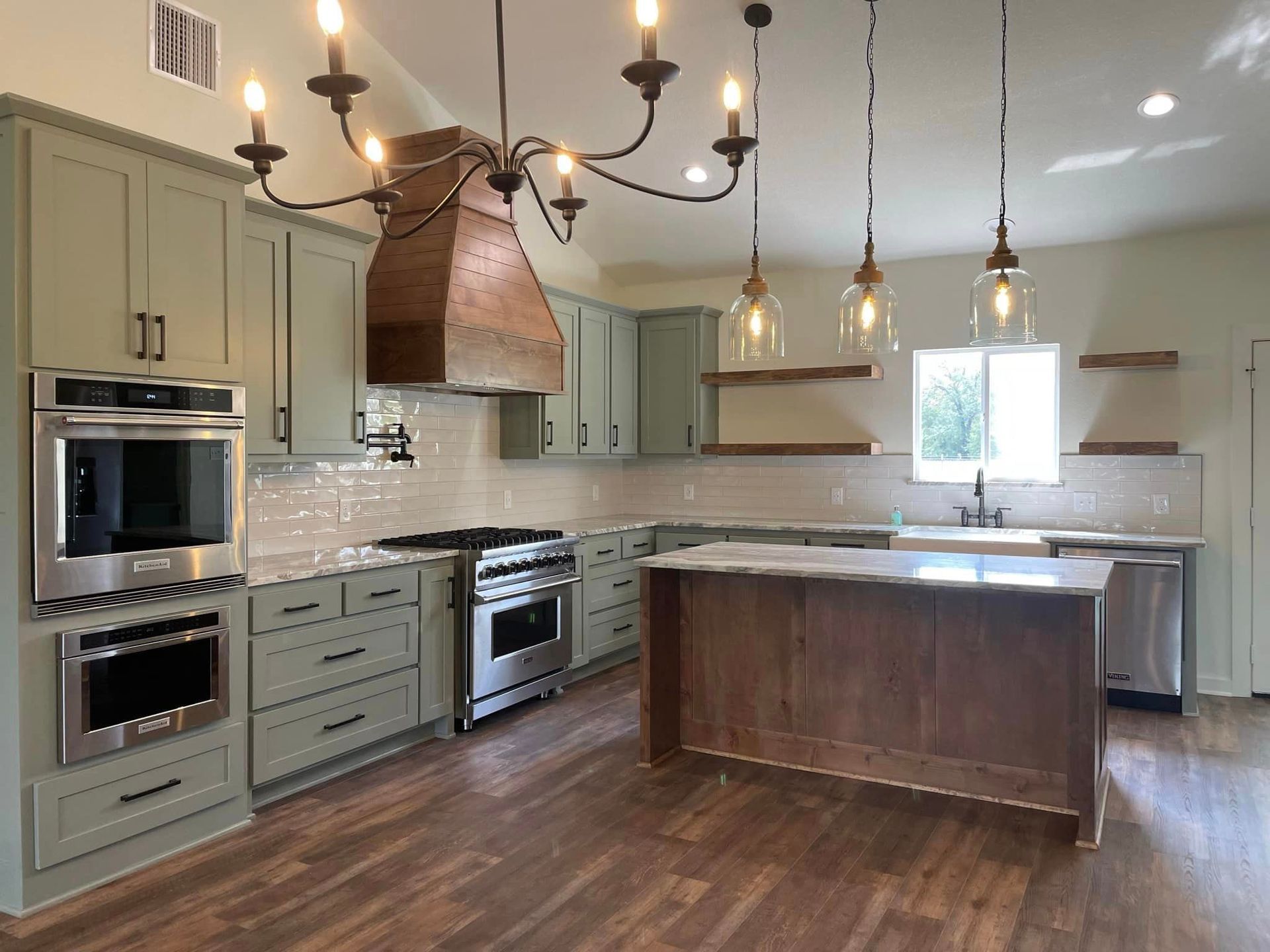 A kitchen with green cabinets and stainless steel appliances